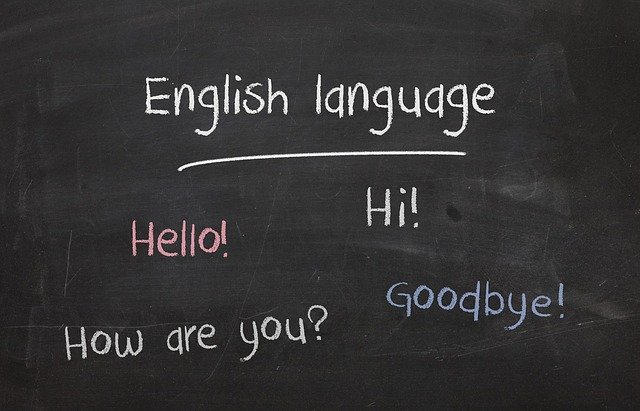 Chalk writing on a black board with the text: English language; hello! hi! how are you? goodbye!